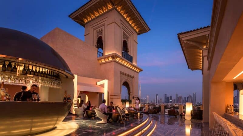 Mercury Lounge at Four Seasons Jumeirah just after sunset with a bar tender making cocktails and people enjoying the dubai skyline view