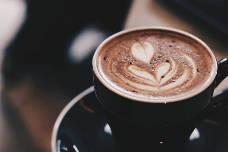 Close up of a coffee cup in a cafe in Dubai in a black cup with a coffee with latte art in the milk