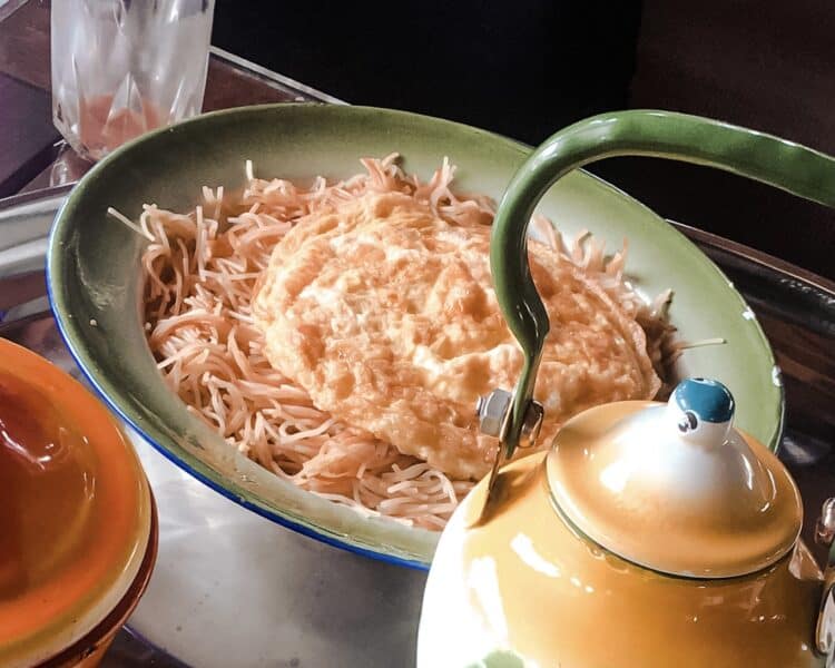 A small egg omlette served on top of sweet vermicelli noodles on a tradtional Emirati tin plate for a food called Balaleet