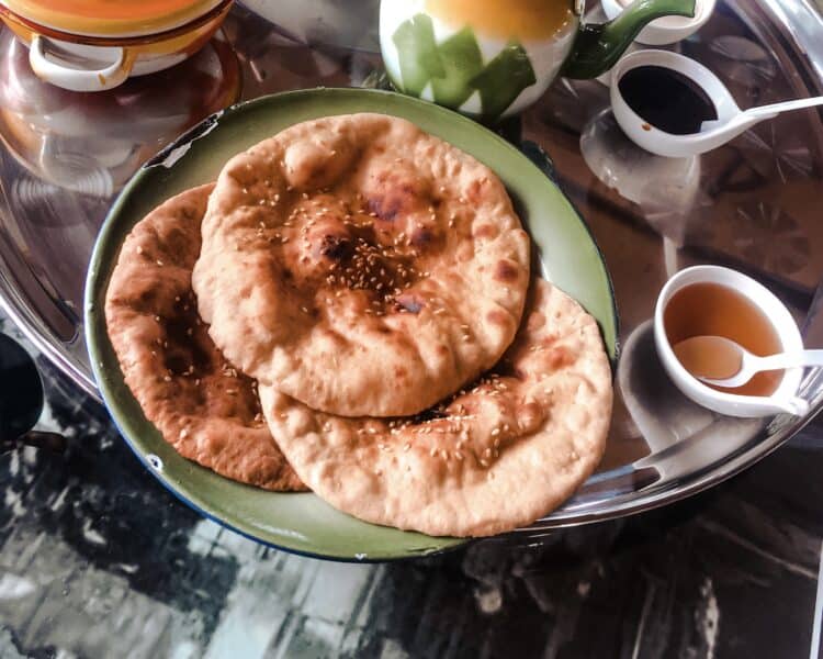 Khameer Emirati bread sprinkled with sesame seeds served on tin plate with honey on a large silver platter