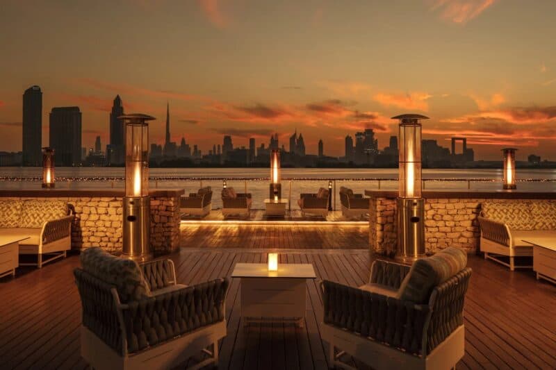Tables and chairs at QDs dubai creek as the sun sets and looking directly onto Dubai Creek view