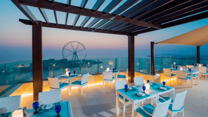 A view at sunset of Ain Dubai and the outdoor seating area on the terrace at Pure Sky Bar. Located on the roof ot the Hilton at Jumeirah Beach Residences or JBR