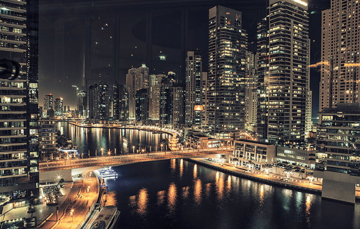 Nightime view of Dubai Marina waters surrounded by sky scrapers as seen from Atelier M in Pier 7 at Dubai Marina
