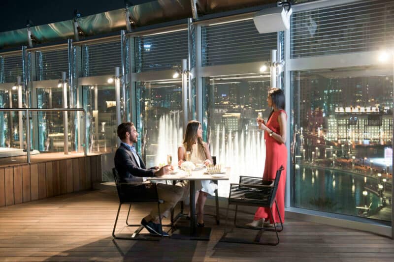 A couple overlooking the desert fountain on the outdoor terrace at Burj Club