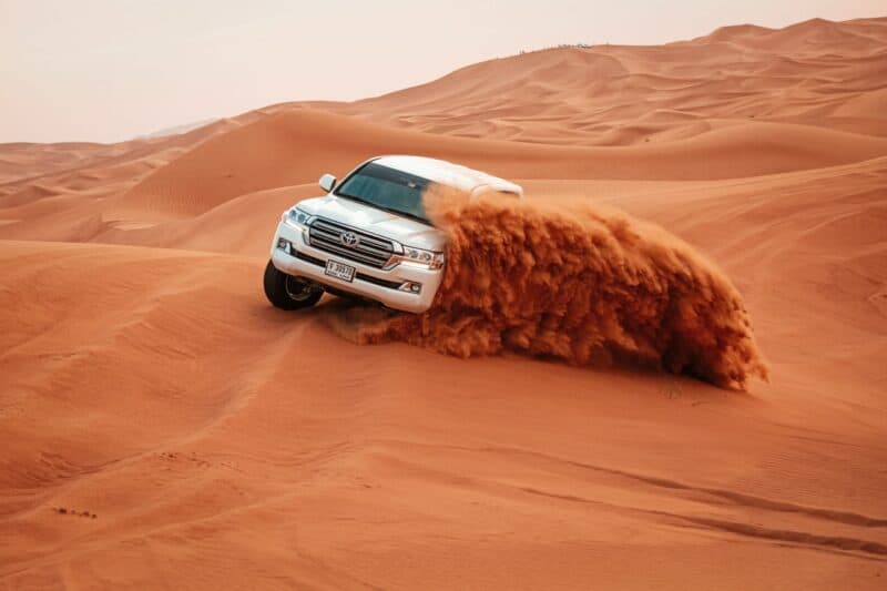 A 4 by 4 vehicle doing slides in the sand on a desert safari causing the sand to fly through the air