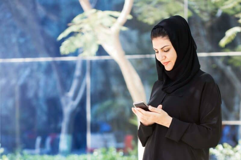An Emirati woman outside with her mobile phone and local sim card