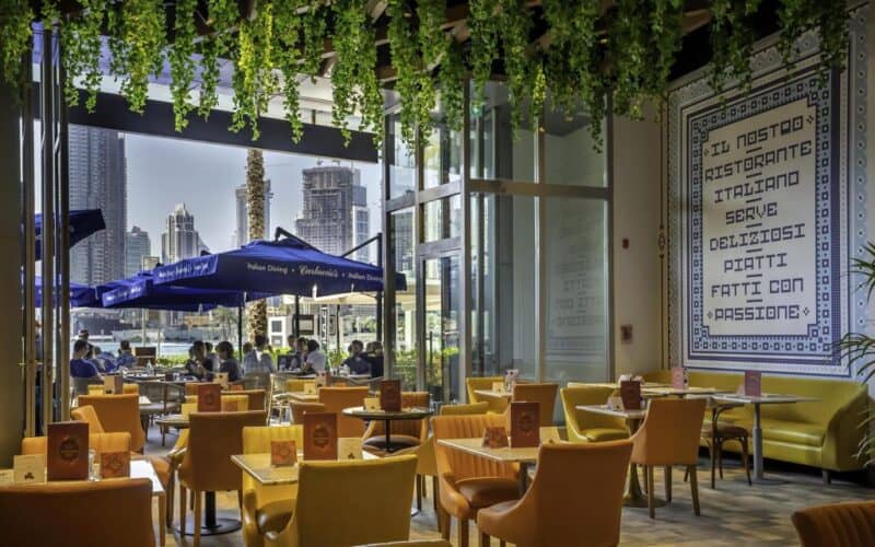 Interiors of Carluccio's with yellow seats and Italian style decoration with a view towards Dubai Fountain and Burj Khalifa