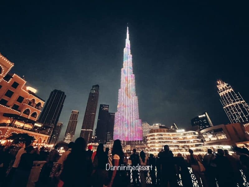 Burj Khalifa lit up at night as crowds of people watch the Burj Khalifa light show