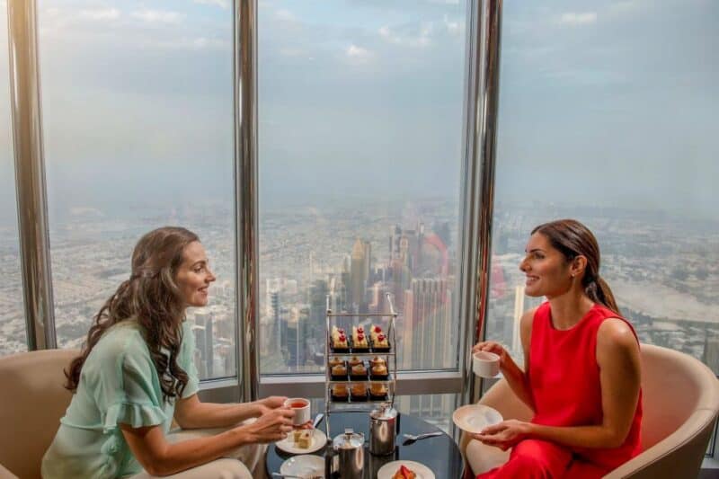 Two friends enjoying the afternoon tea at At The Top VIP lounge in Burj Khalifa with tea and the view over Dubai