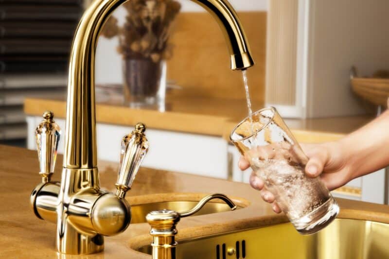 A hand holding a glass under a gold tap in a Dubai hotel