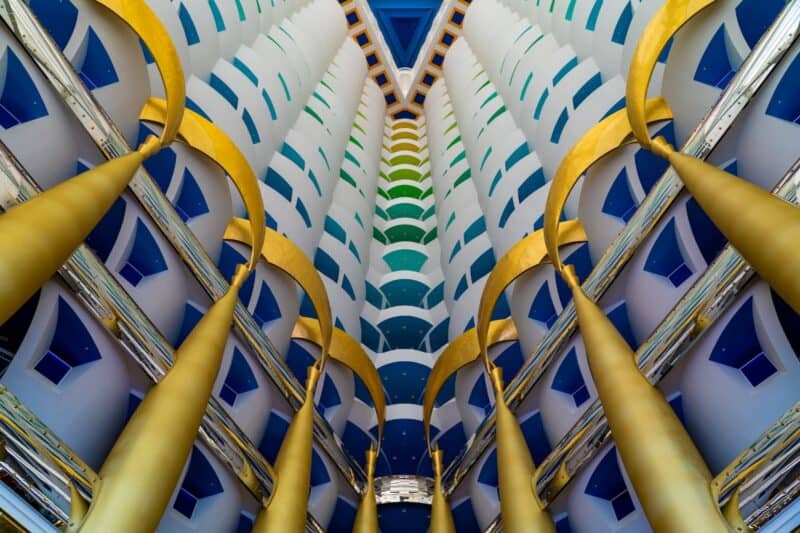 Inside the lobby looking up towards the higher floors and rooms inside the Burj Al Arab with columns covered in gold leaf and blue painted ceilings of the communal areas