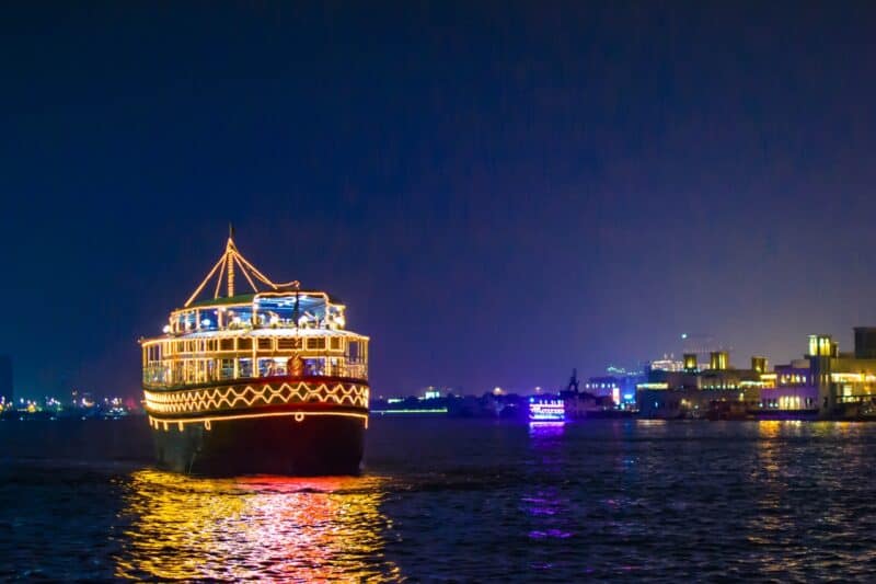 A Dhow cruise ship lit up and sailing down Dubai Creek