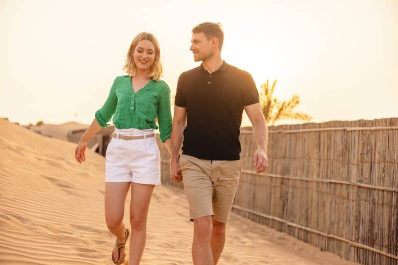 a couple holding hands in dubai in the desert and showing a public display of affection