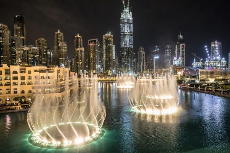 Dubai Fountain lit up at night with the watch jets shooting up and dancing with the Downtown Dubai skyline in the background