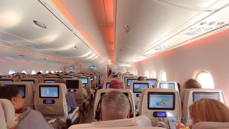 Inside an Emirates flight with older entertainmentv screens in an A380 airplanes with passengers using the In-flight Entertainment system 