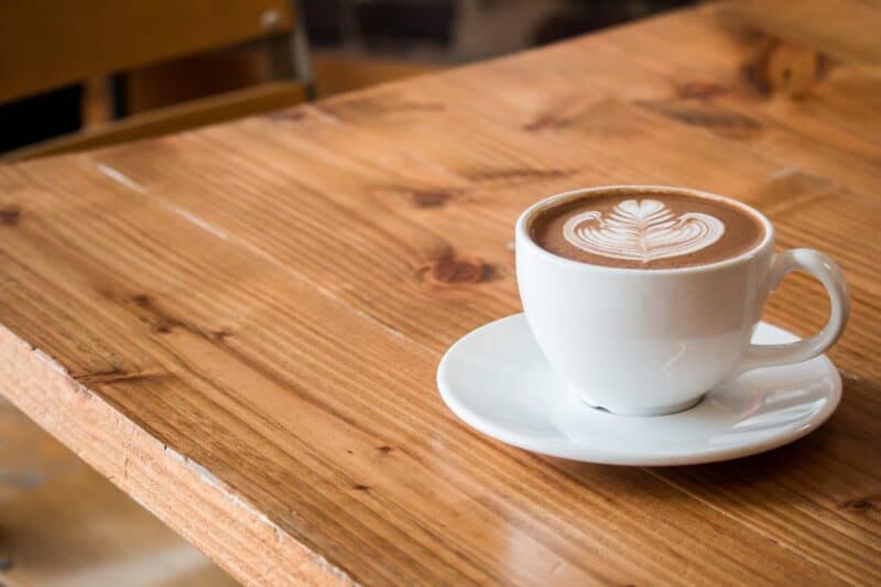 Flat white coffee in a white cup on a wooden table