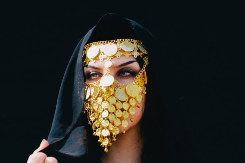 A woman wearing a more decorated burqu or battoulah with gold coins hanging off the mask and a black shayla to cover her hair