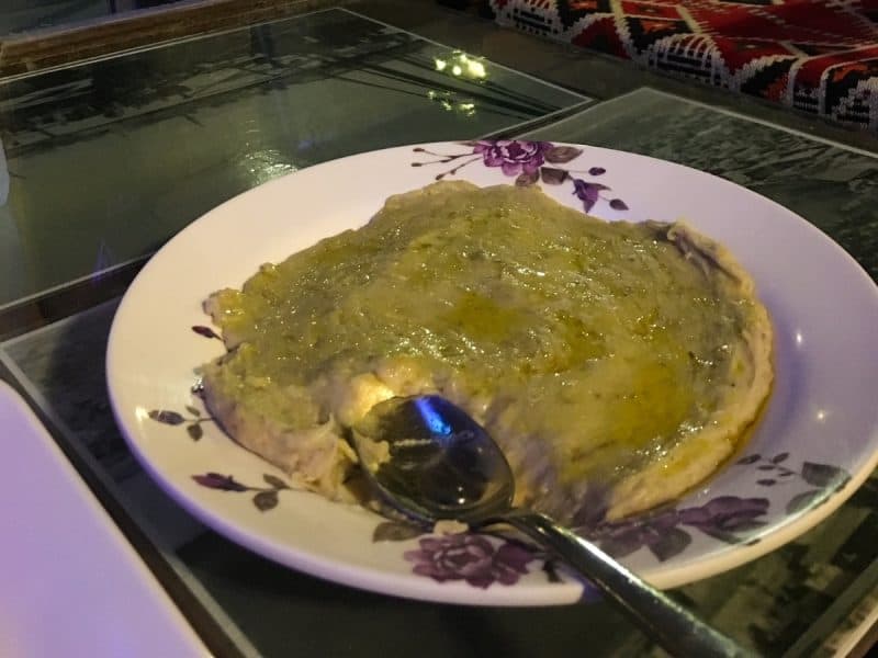 A bowl of harees with ghee melted on top and a spoon where I'd eaten on mouthful first to try