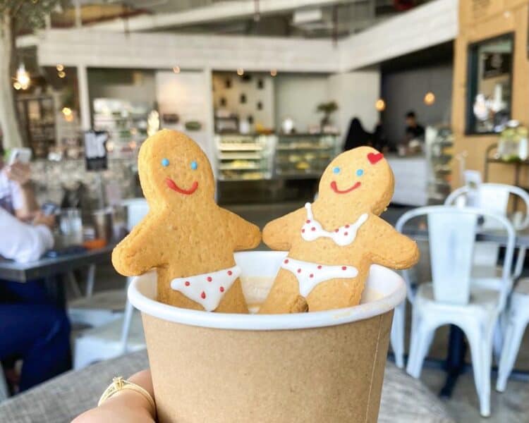 A gingerbread man and woman for children as snacks sat in a hot drink at Lime Tree Cafe on Sheikh Zayed Road in Dubai with the interiors of the cafe in the background