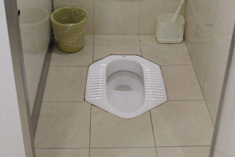 middle eastern toilet or squat toilet with beige tiles and a small waste paper basket, popular in Middle East and Asian countries