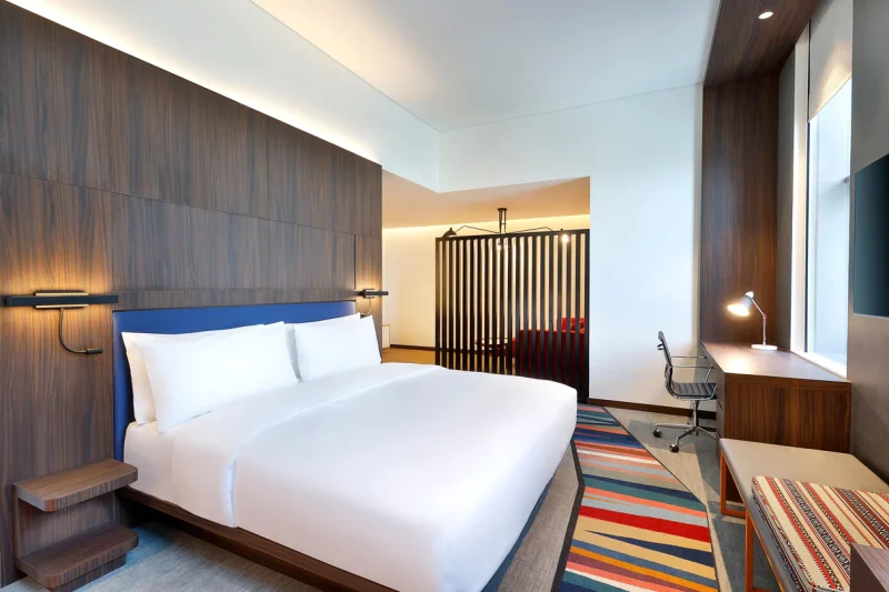 Modern and contemporary room with king size bed and desk inside Aloft Dubai Airport