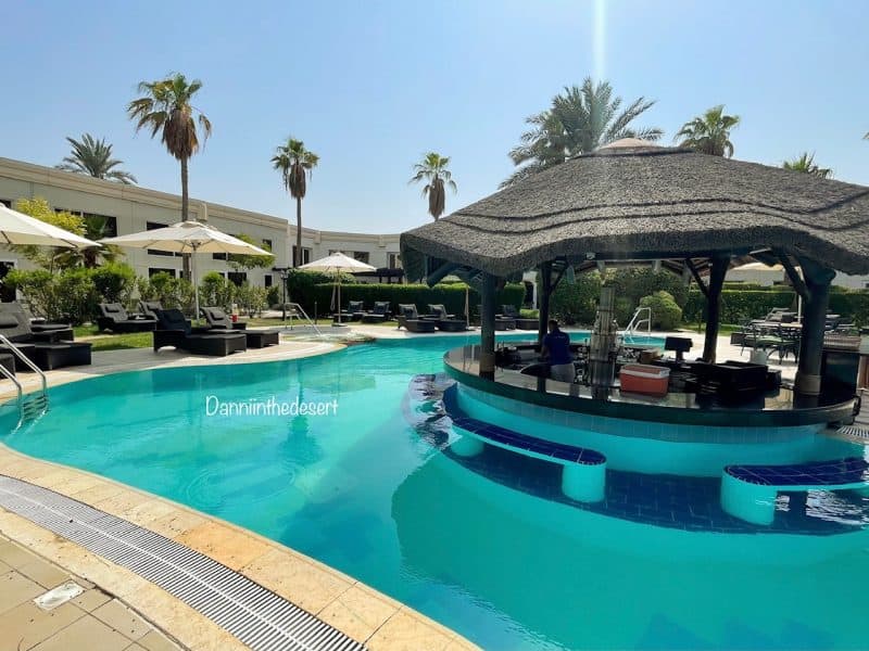 Luxurious swimming pool area with swim up bar at Le Meridien Dubai Hotel Royal