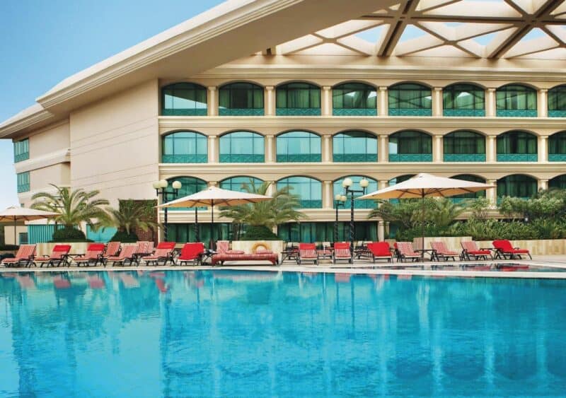 Outdoor swimming pool at the back of Movenpick Grand Al Bustan with bright red sunloungers