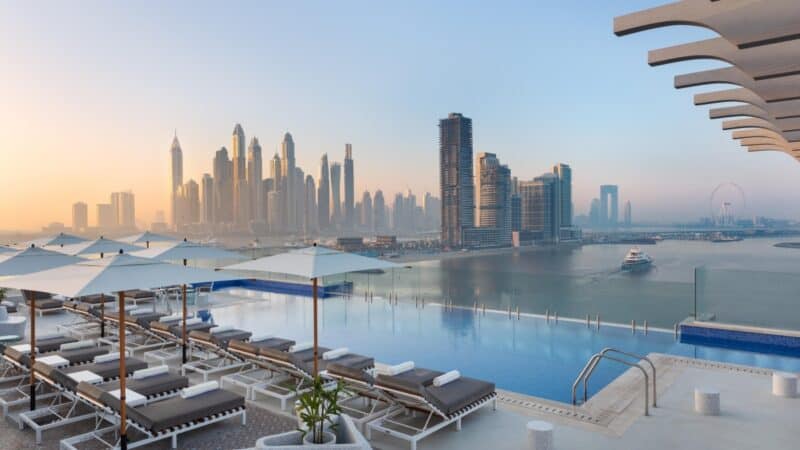 View of Dubai Marina and swimming pool with sun loungers and umbrellas at Voco Dubai The Palm