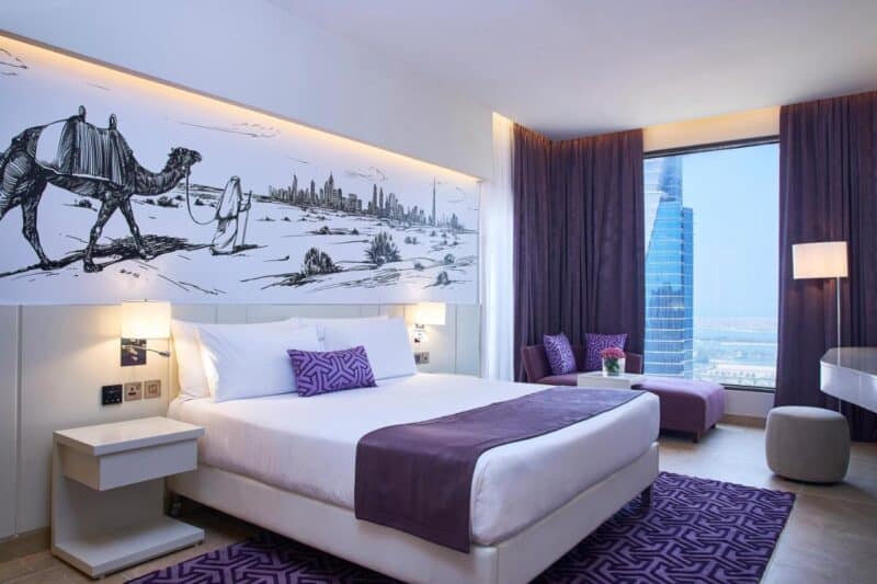 Unique purple and white interiors with an image of a camel and the Dubai skyline on the art in the room at Mercure Hotel Barsha Heights