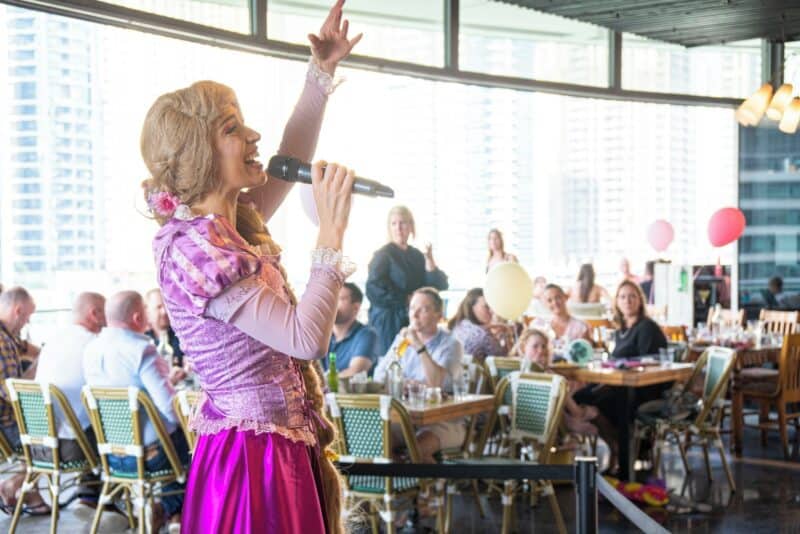 Singer performing at the family brunch at The Scene in Pier 7 and dresses as a Disney princess with diners in the background 