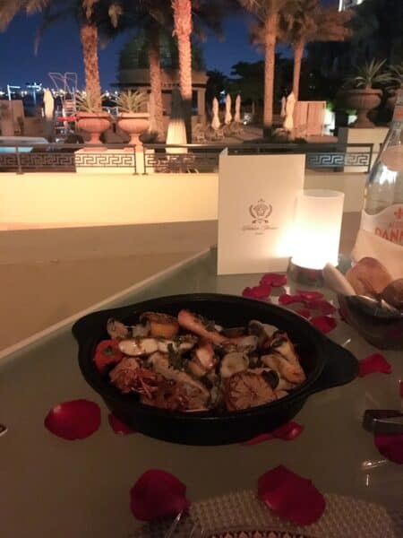 Seafood special dish at Vanitas Dubai with a table covered in red rose petals for an engagement and the view of Dubai Creek in the background