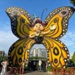 Large cartoon butterfly as you walk into the entrance of Dubai Butterfly Garden to welcome visitors with a few people waiting outside