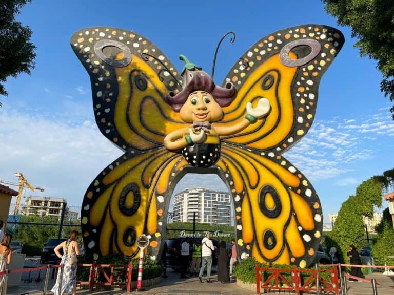 Large cartoon butterfly as you walk into the entrance of Dubai Butterfly Garden to welcome visitors with a few people waiting outside