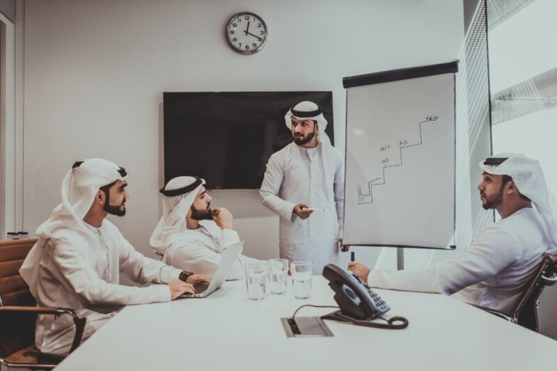 Emirati men wearing traditional Emirati dress while having a boardroom meeting at work