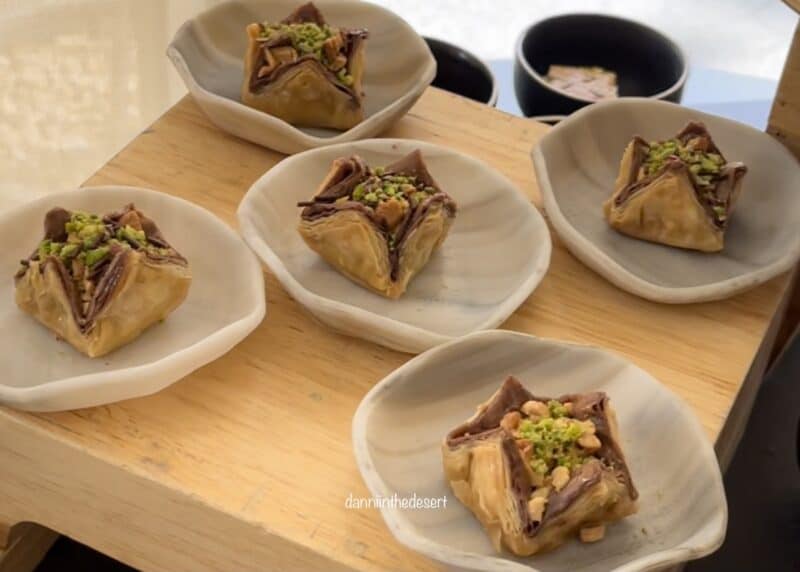 Several Baklava pieces on individual small plates ready to be eaten on a wooden table