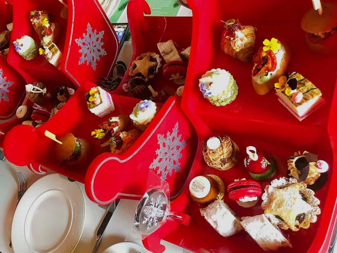 Festive afternoon tea at Fairmont The Palm with special sleigh serving trays and Christmas coloured pastries set on the table