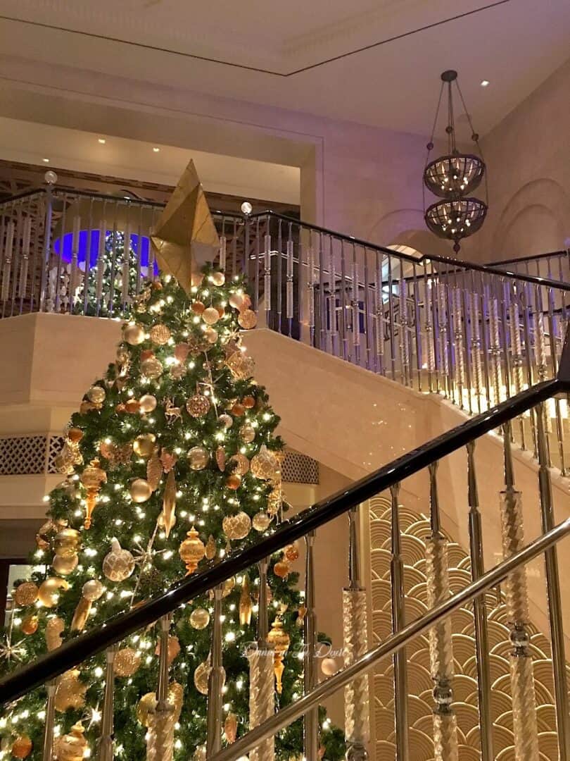 Large Christmas tree at Four Seasons Jumeirah in Dubai reaching up to the second floor with the stair case wrapping around it