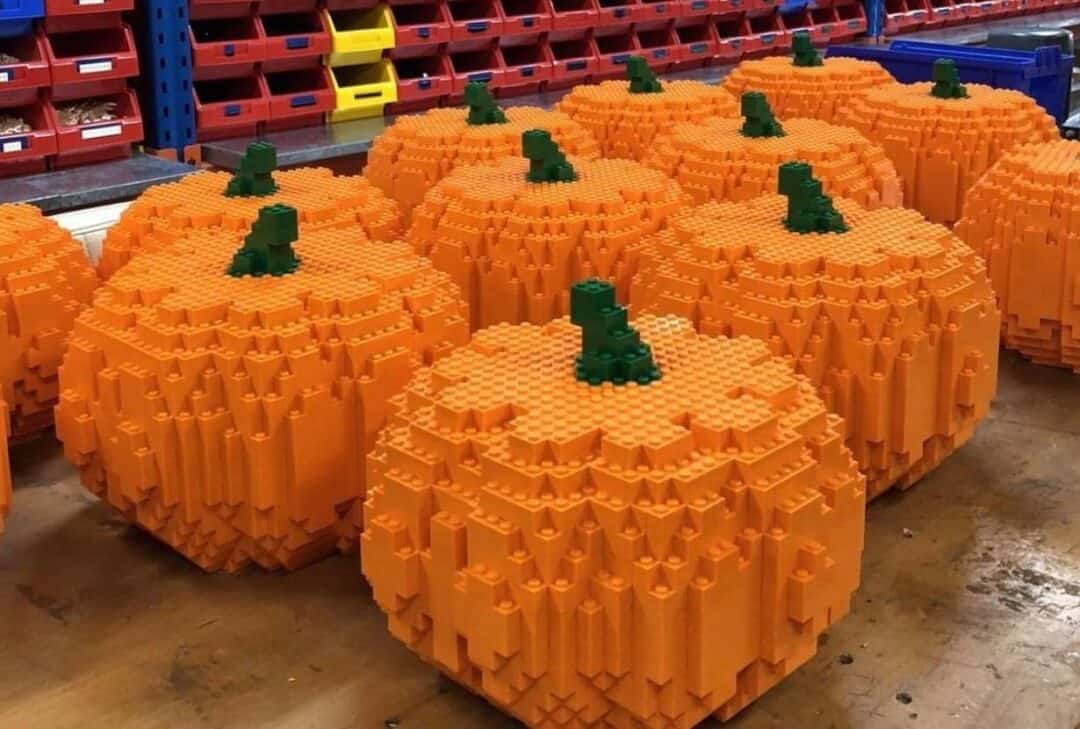 Pumpkins made entirely out of lego blocks sitting on a wooden table