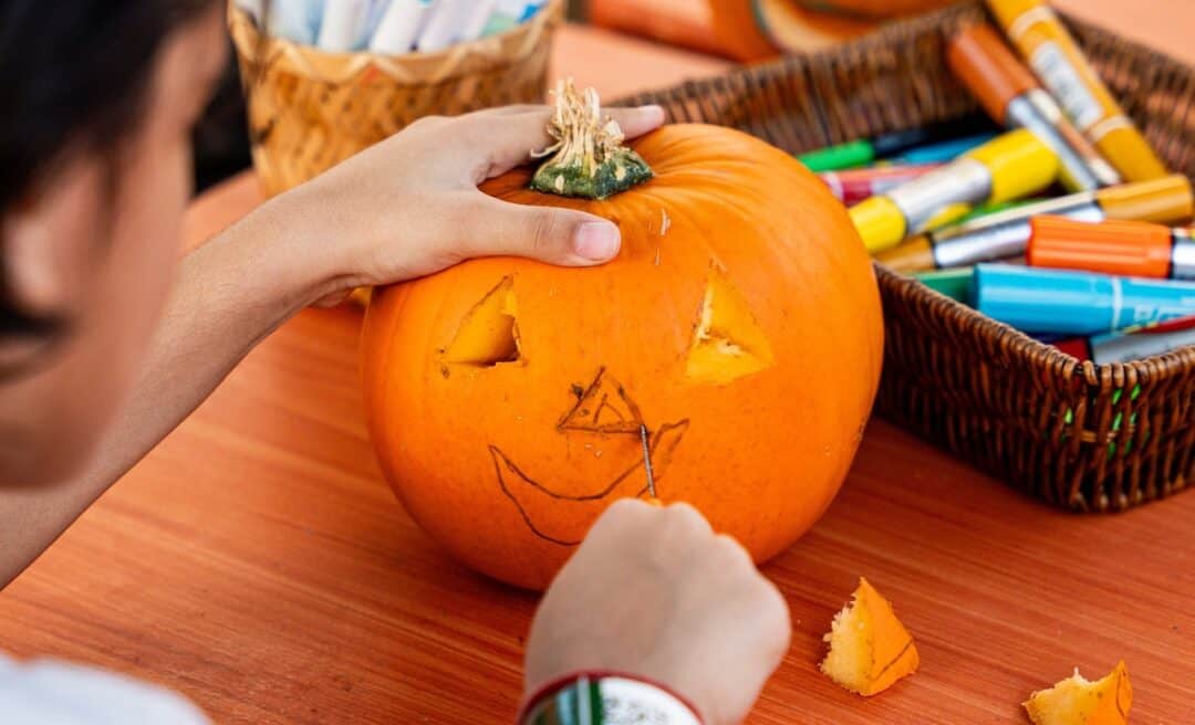 Pumkin carving at an activity table at Green Planet Dubai with the cutter about to cut the pumpkin's nose