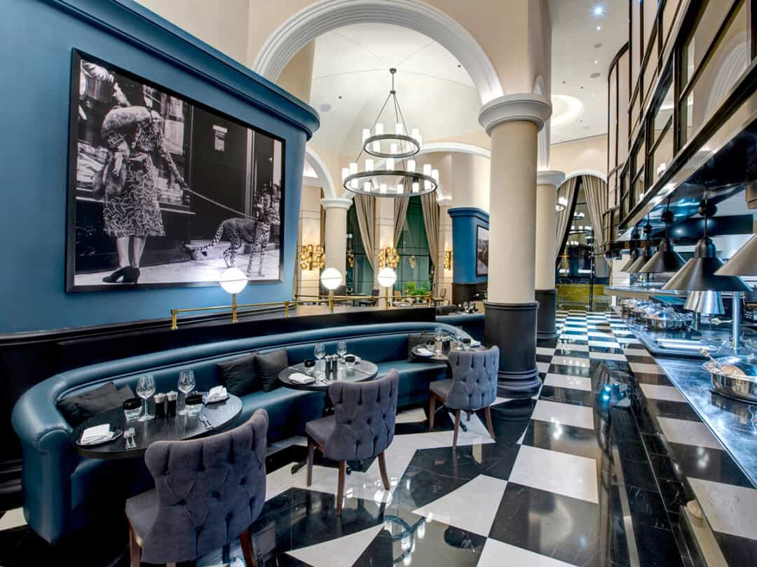 The elegant interiors with black and white marble flooring contrasting the blue walls and blue leather sofas at Great British Restaurant