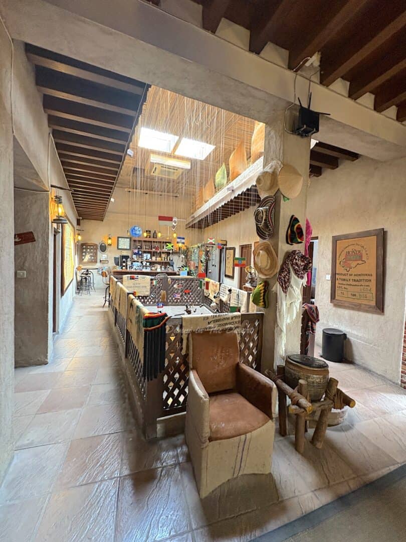 Various items related to coffee hang on the walls and columns of Dubai's coffee museum with traditional wooden beams and railings inside the upper floor of the historical building