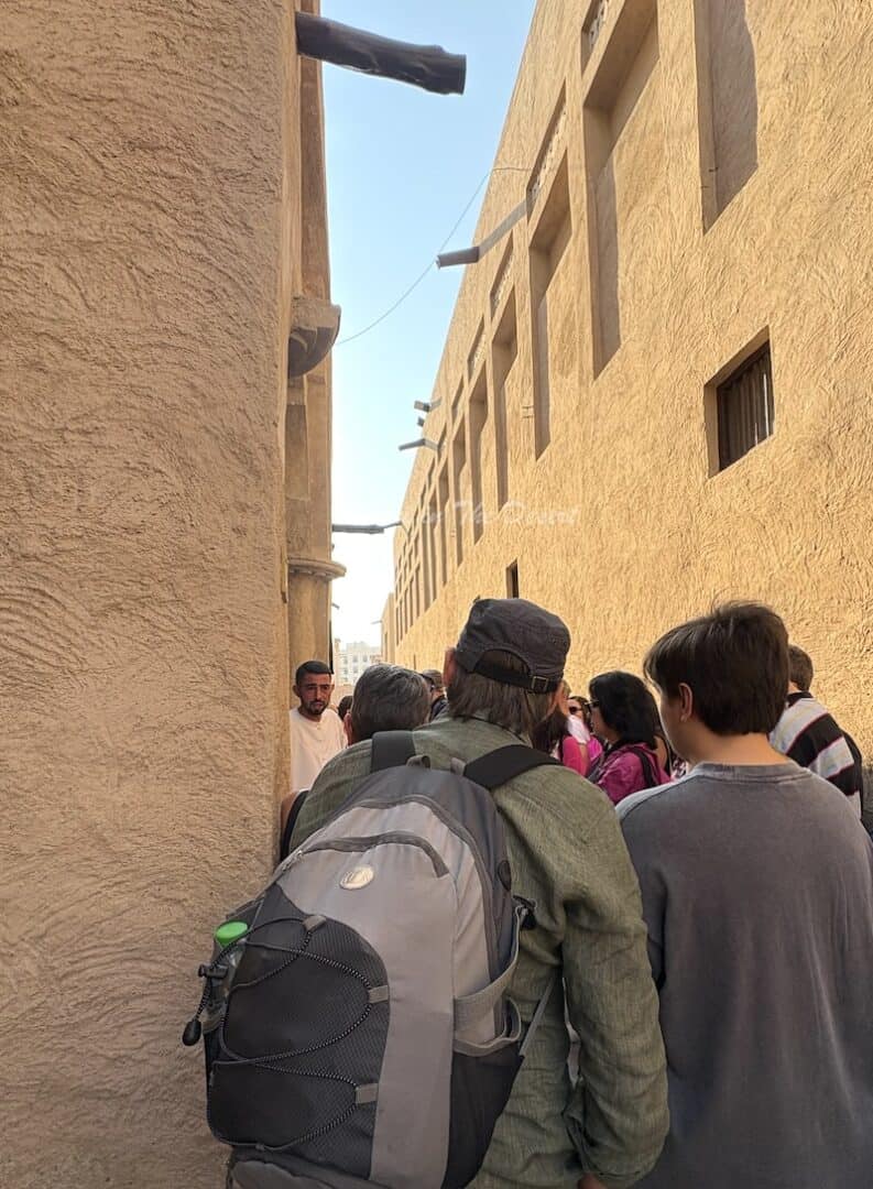 Tour guide standing in front of the historic buildings in Dubai explaining the history of the area to a small crowd of people on a walking tour